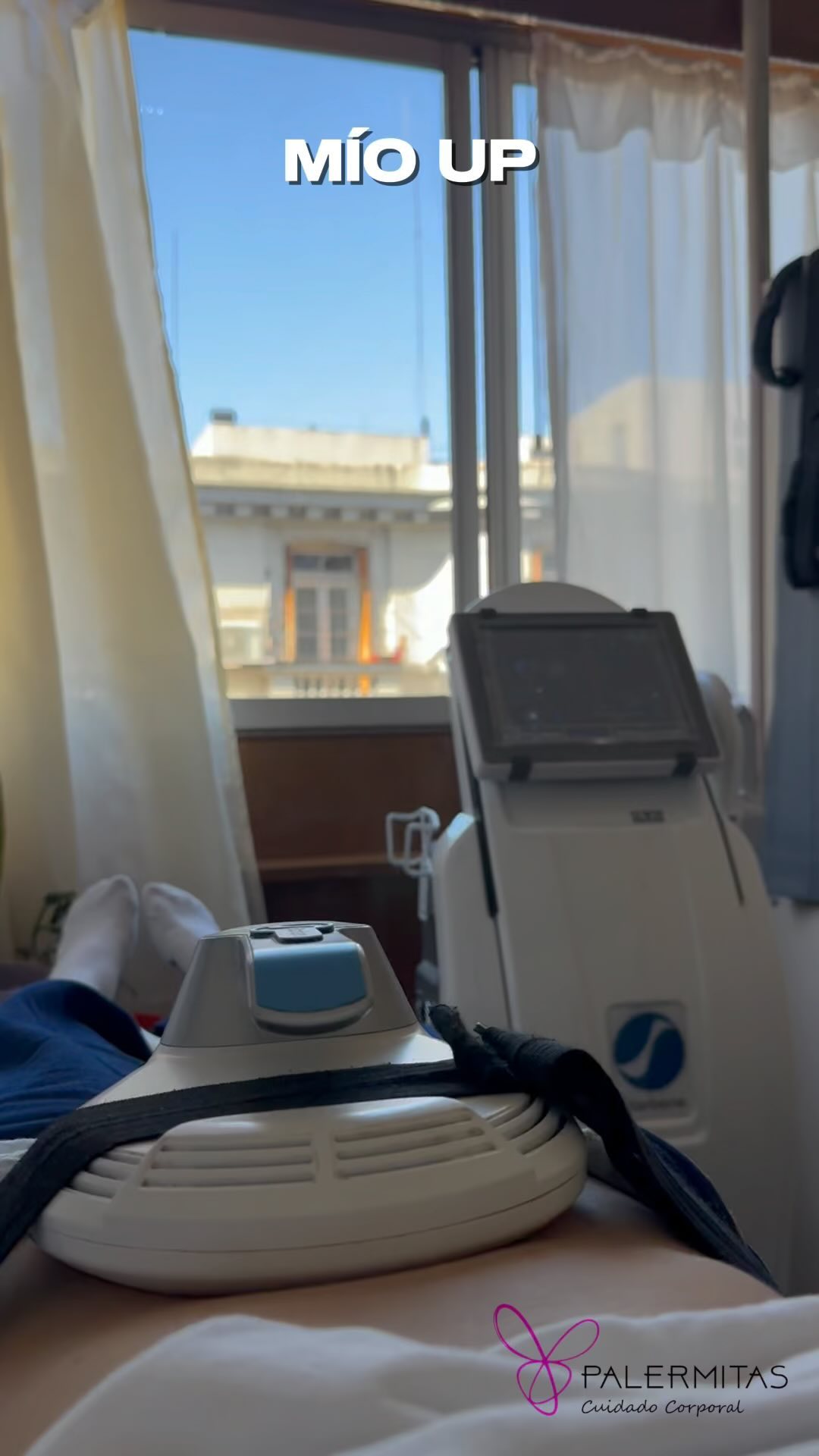 Una cabina de Palermitas: el equipo de Mio Up junto a un gran ventanal con cortinas blancas que da a los techos de Palermo, y una paciente en la camilla con un aplicador sobre la zona